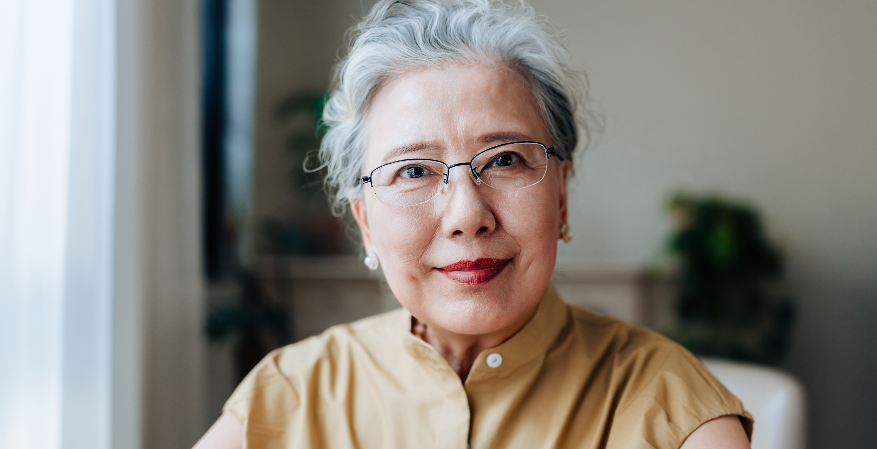 Older woman smiling and sitting in a home office.